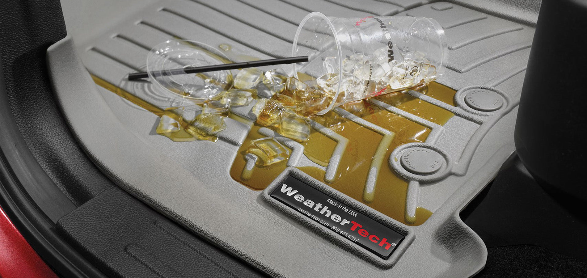 A tipped-over cup with spilled iced drink and ice cubes on a WeatherTech car floor mat, showing the mats ability to contain messes and protect the car’s interior.