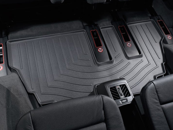 A close-up view of black WeatherTech FloorLiner for BMW X5 (E70) 2007-2013 3rd row installed in a vehicle’s rear, offering superior floor protection and showing visible air vents behind the center console.