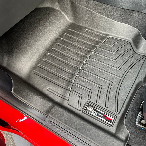 A black WeatherTech Floorliner for Mazda BT-50 (2012-2020) & Ford Ranger (2012-2022) 1st row is shown fitted in the front passenger footwell, featuring deep grooves and a visible WeatherTech logo near the edge.