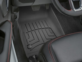 Close-up of a Jeep Wrangler 2-Door (2018-) 2nd row with a black WeatherTech Floor Liner HP, showing grooves and logo for top-notch floor protection, next to a black leather seat with red stitching.