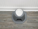 The WeatherTech Single Elevated Pet Feeding System by WeatherTech, in gray and white, sits spill-proof with a wide base on a wood-look floor against a white wainscoted wall.