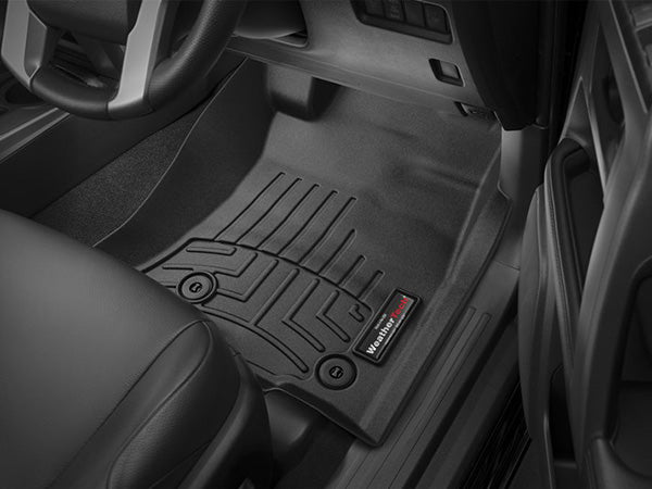 Driver-side view of a Toyota Land Cruiser Prado J150 (2010-) interior featuring a black WeatherTech FloorLiner in the 1st row, with raised ridges and logo near the pedals, providing superior carpet protection.