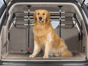 A golden retriever sits in the back of an SUV with a WeatherTech Pet Barrier installed behind the rear seats, looking at the camera.