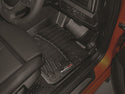 Close-up of the driver’s side floor with a black WeatherTech Floorliner for BMW 1 Series Hatch (F20/F21, 2012-2019, 1st Row), black leather seat, part of the dashboard, and an orange door frame—all protecting your interior carpet.