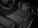 Close-up of a WeatherTech FloorLiner for BMW 5 Series Sedan/Wagon (2014-2017, F10/F11), installed on the drivers side. Ridged grooves and precise fit protect under the pedals and door sill labeled BMW.