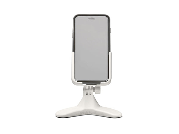 A smartphone stands upright in the Weathertech DeskFone White, a desktop phone holder with a wide, stable base and adjustable stand, set against a plain white background.