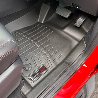 Close-up of a Mazda BT-50/Ford Ranger (2012-2022) 1st Row WeatherTech Floorliner in black, fitting neatly under the pedals with visible seat and red door frame for superior floor protection.