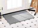 A WeatherTech Carpet Mat by WeatherTech in light gray sits on a white tiled floor with black diamond accents near a glass door; a coat hangs on a nearby rack.