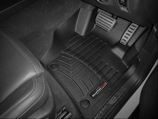 Driver side view of a Porsche Cayenne 3rd Gen (2013-2017) shows a black WeatherTech Floorliner - 1st Row, offering superior floor protection under the pedals and next to the black leather seat.