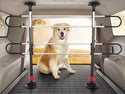 A large, fluffy dog sits in the back of a car behind a sturdy WeatherTech Pet Barrier. The dog gazes forward with its mouth open, while trees and sunlight are visible outside the rear window.