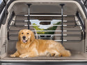 A golden retriever rests comfortably in a car’s trunk, separated from the cabin by a WeatherTech Pet Barrier. The parked car sits by trees visible through the window.