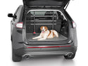 A brown and white dog lies in the cargo area of an SUV with its rear hatch open. The trunk features a protective mat and a WeatherTech Pet Barrier installed behind the back seats for added safety.