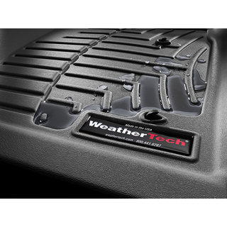 Close-up of a black WeatherTech FloorLiner HP for Jeep Wrangler (2018-) 1st Row, with water droplets on its ridged, textured surface for superior protection. The WeatherTech logo and contact label are visible above the interior carpet.