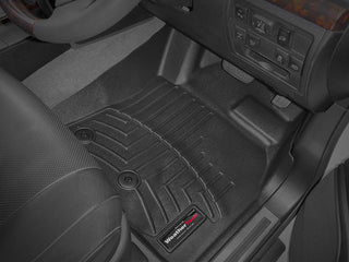Close-up of a WeatherTech FloorLiner for Toyota Land Cruiser V8 J200 (2012-2019) 1st Row, showing its precise laser-measured grooves and retention buttons, plus glimpses of the seat and dashboard controls.