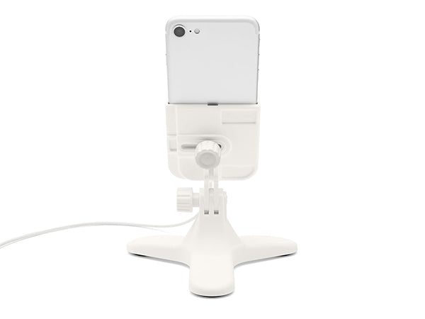 A Weathertech DeskFone White securely holds a smartphone vertically on a desk with its adjustable knob for stability. A charging cable is connected at the bottom.